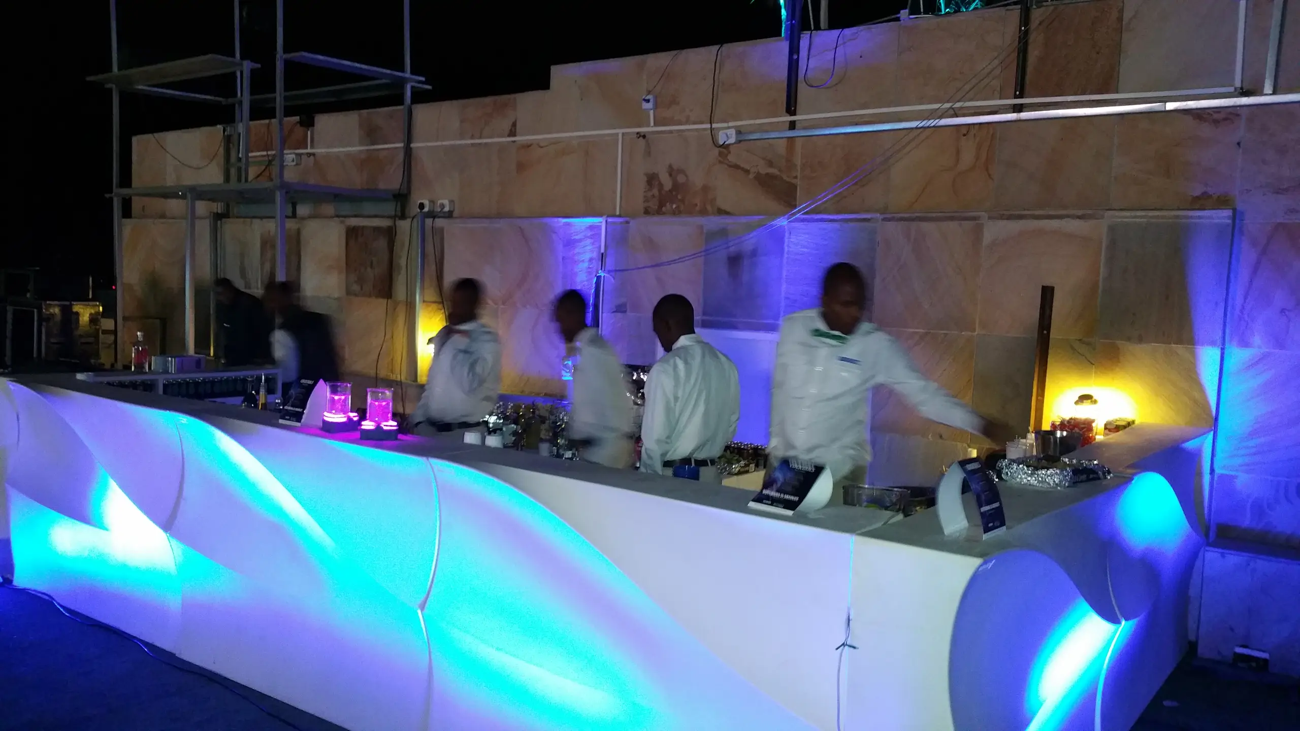 A curved white bar lit blue from inside, with chefs working behind it