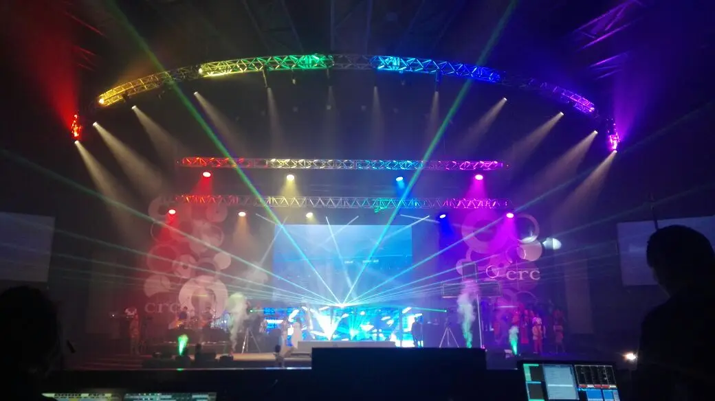 A stage with moving lights, coloured beams and a laser arc over the band