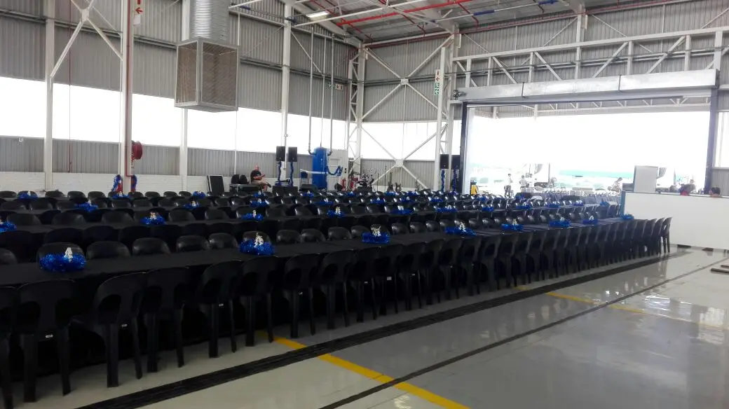 A hangar set up with long rows of chairs and a sound system for a large audience