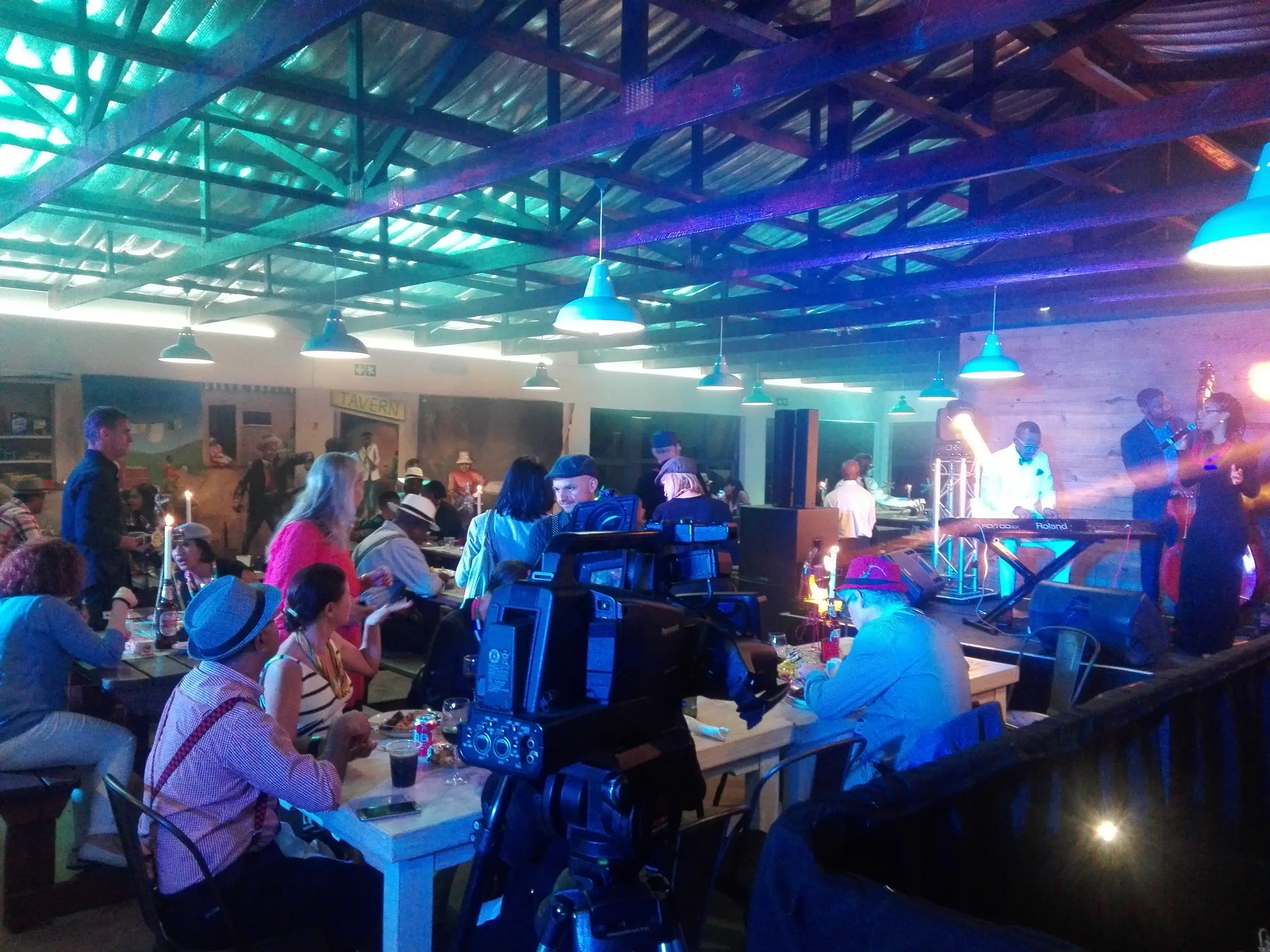 A full hall under blue and cyan lights, with a camera crew filming