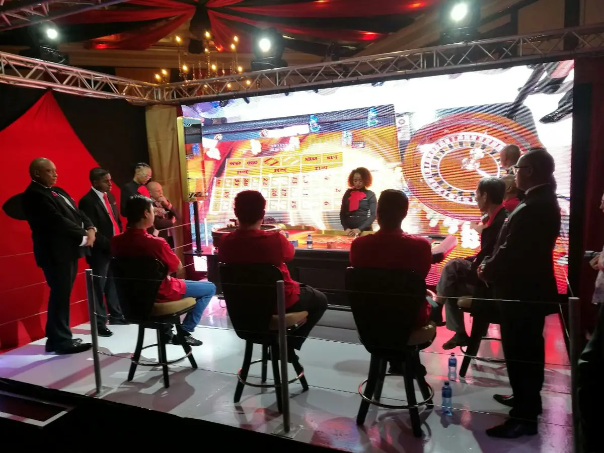 A casino-themed set with a large LED wall, guests at high tables in front of it